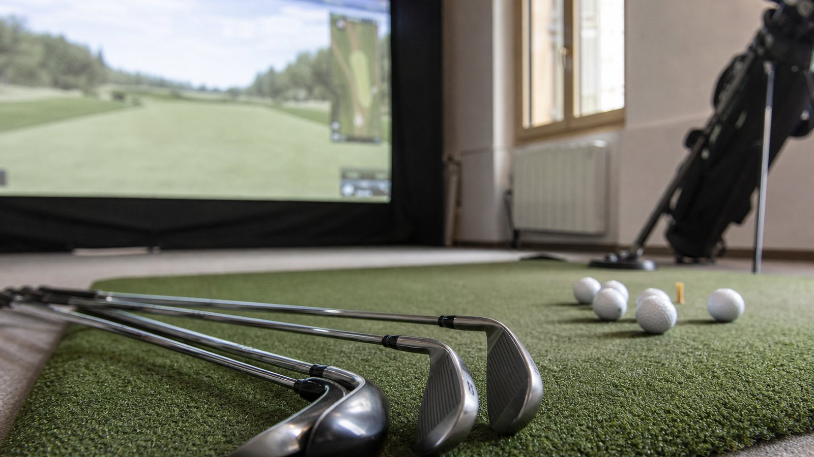 Clubs, gant et balles propres disposés près du tapis de frappe d'un simulateur de golf indoor